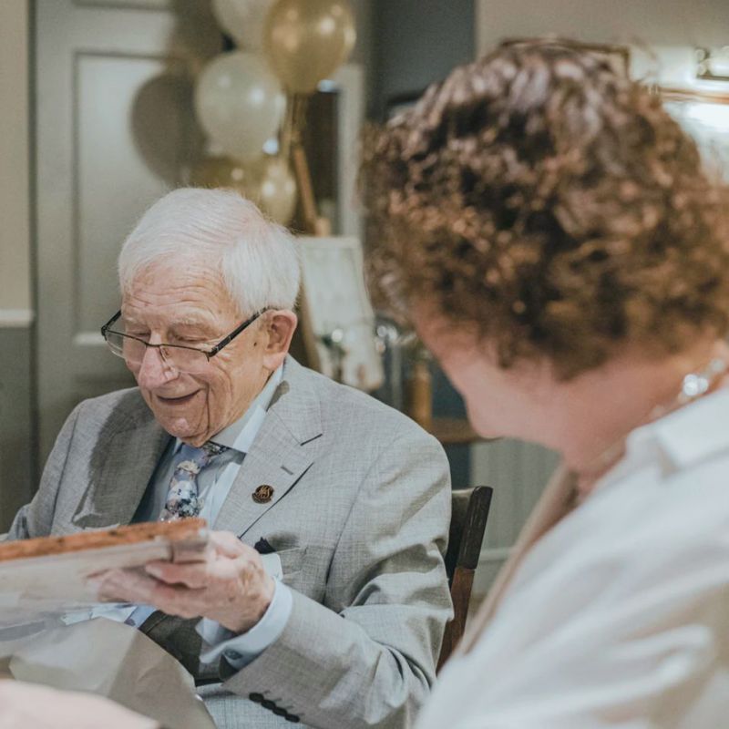 An elderly father and his daughter sitting at a table