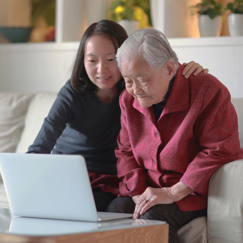 A woman shows her grandmother a website on a laptop